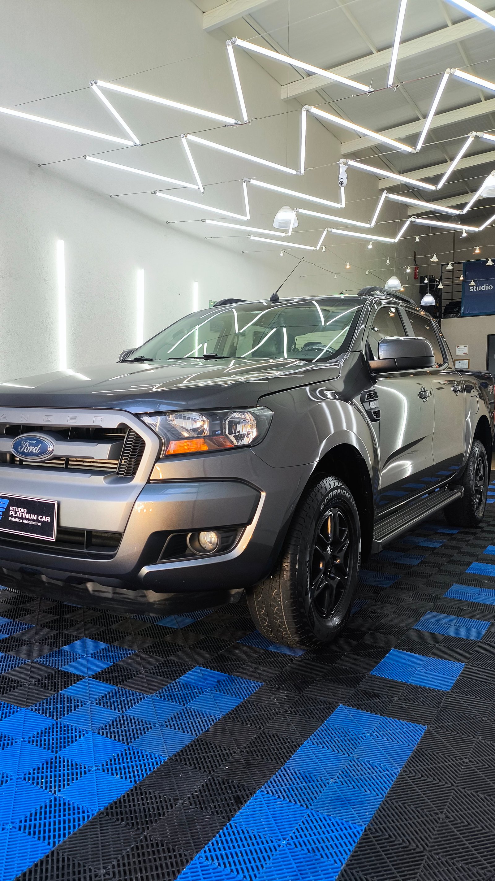 Ford Ranger cinza com pintura espelhada sob luzes do box após polimento técnico